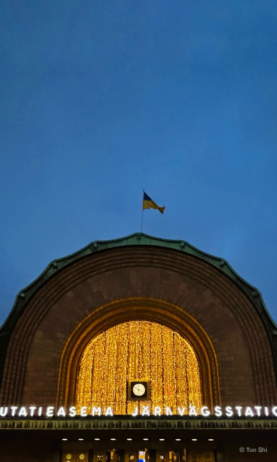 The arch of Helsinki Central Station filled with golden lights at night
