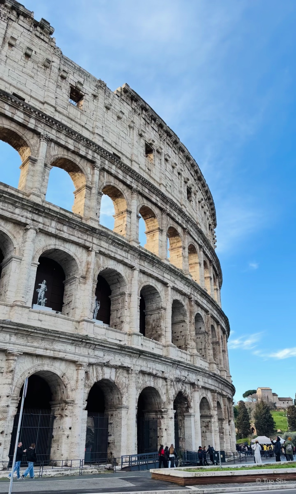 The outer arches of the Colosseum under a pale sky