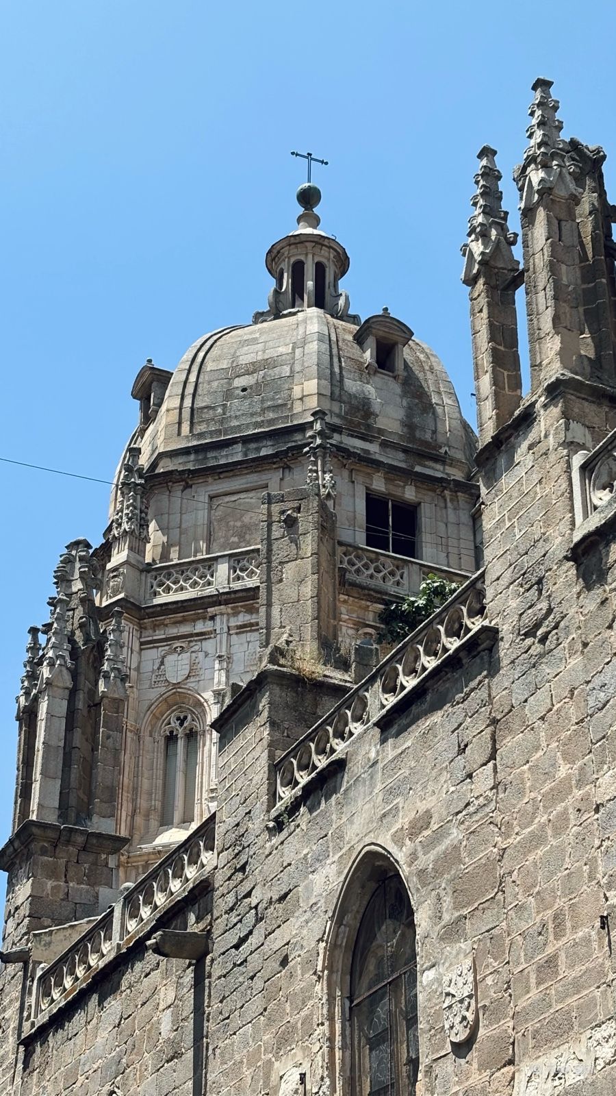The dome and Gothic stone towers of Toledo Cathedral against a blue sky